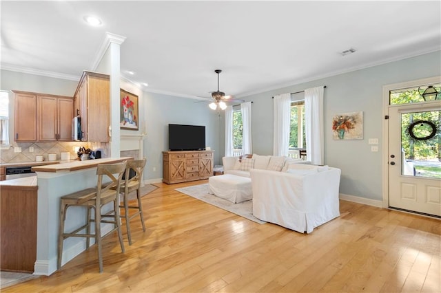 living room featuring crown molding, a healthy amount of sunlight, and light wood-type flooring