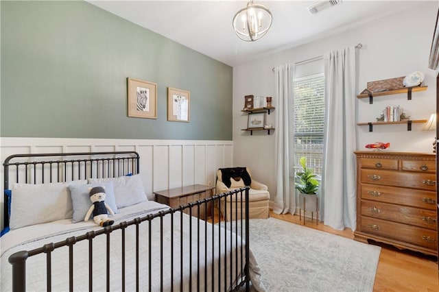 bedroom with light hardwood / wood-style flooring and a notable chandelier