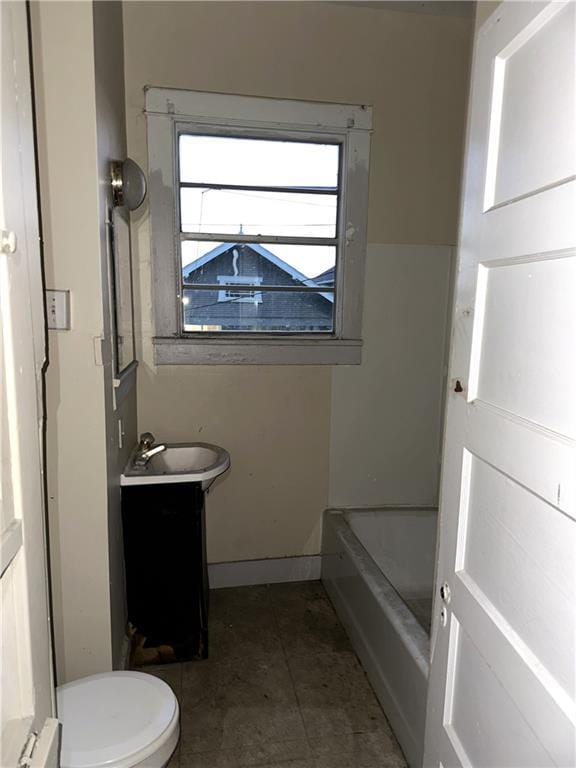 bathroom featuring vanity, toilet, tile patterned flooring, and a washtub