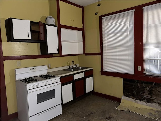 kitchen featuring white range with gas cooktop, sink, and dark tile patterned flooring