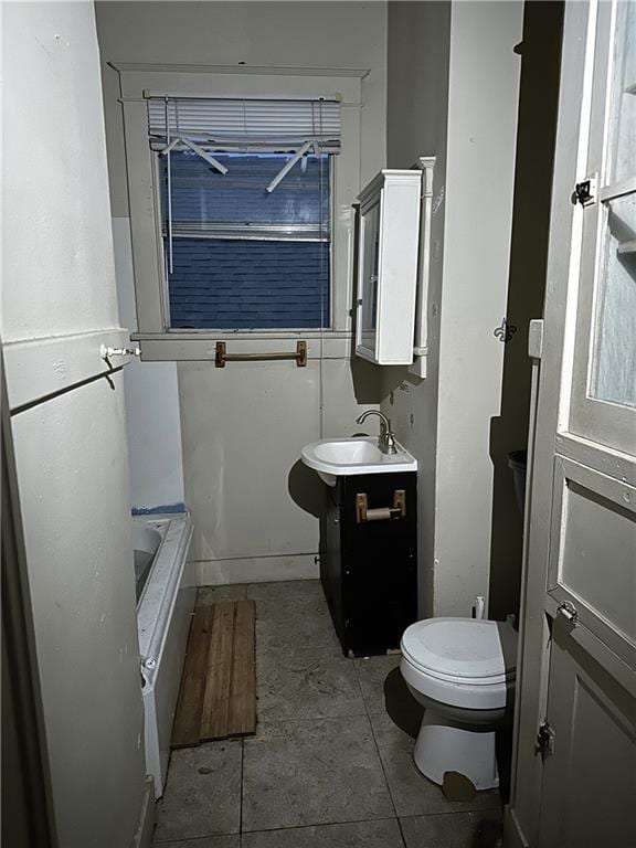 bathroom featuring vanity, a tub, tile patterned floors, and toilet