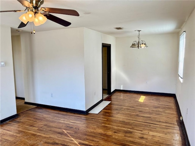 spare room with dark hardwood / wood-style floors and a chandelier