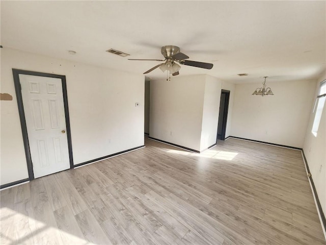 empty room featuring light wood-type flooring, visible vents, baseboards, and ceiling fan with notable chandelier
