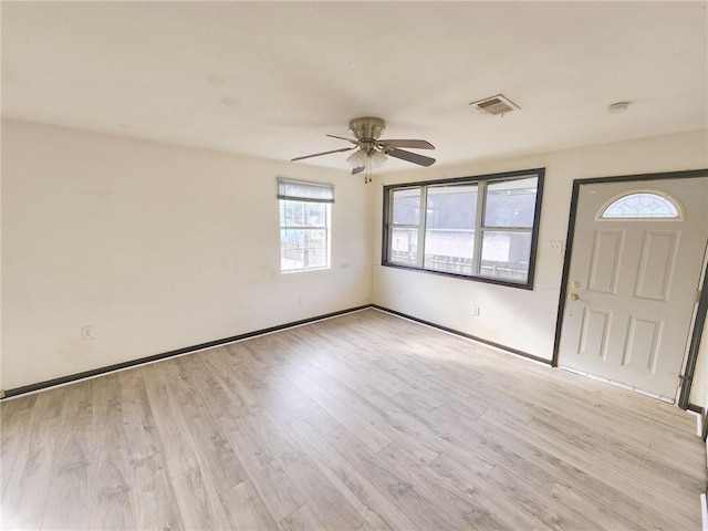 interior space with baseboards, a ceiling fan, visible vents, and light wood-style floors
