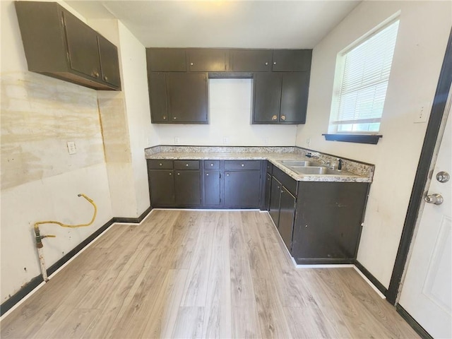 kitchen with light countertops, light wood-style floors, baseboards, and a sink