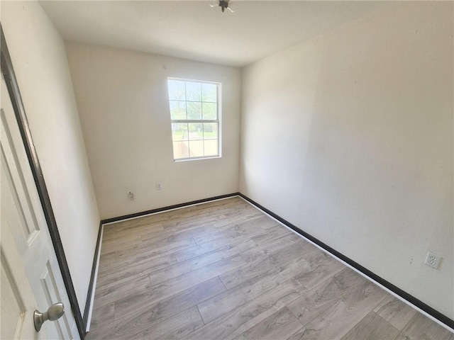 spare room featuring baseboards and wood finished floors