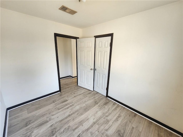 unfurnished bedroom featuring light wood-style floors, visible vents, and baseboards