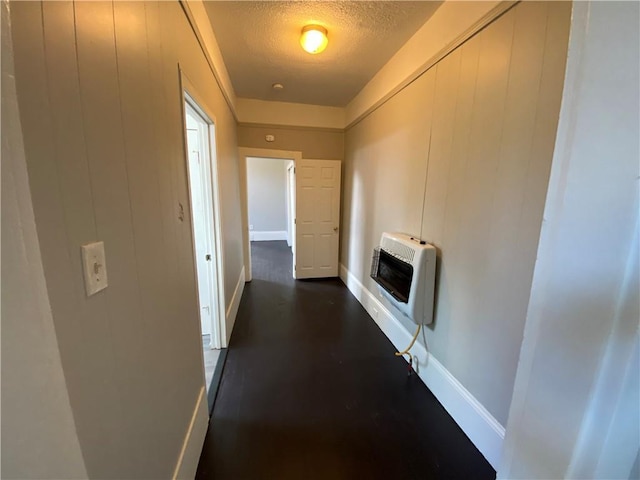 hall featuring dark hardwood / wood-style floors, heating unit, and a textured ceiling