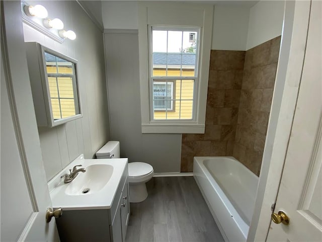 bathroom featuring toilet, vanity, a bath, and hardwood / wood-style floors