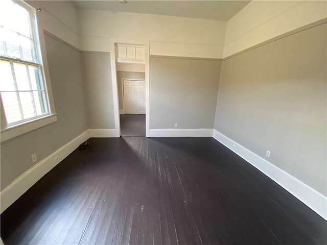 empty room featuring a healthy amount of sunlight and dark wood-type flooring