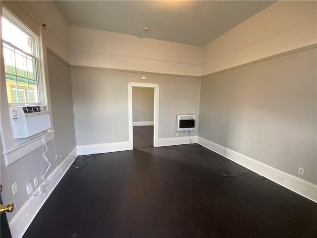 empty room with heating unit, cooling unit, and dark wood-type flooring