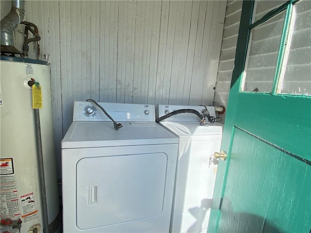 laundry room featuring wooden walls, washing machine and dryer, and gas water heater