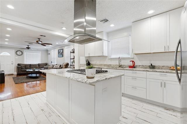 kitchen with island range hood, white cabinets, and a kitchen island