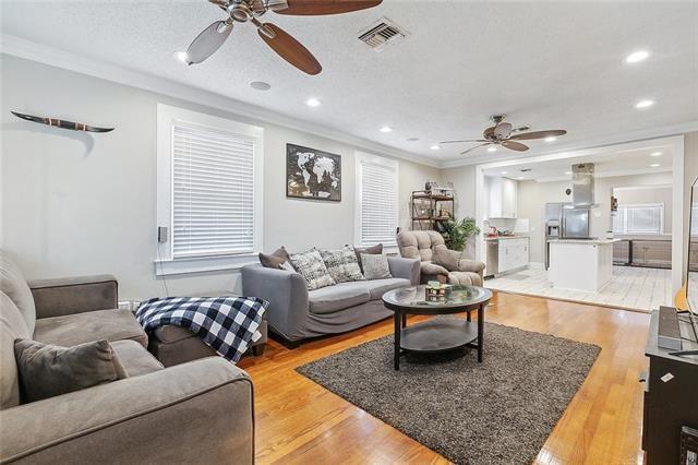 living room featuring crown molding, light hardwood / wood-style flooring, and ceiling fan