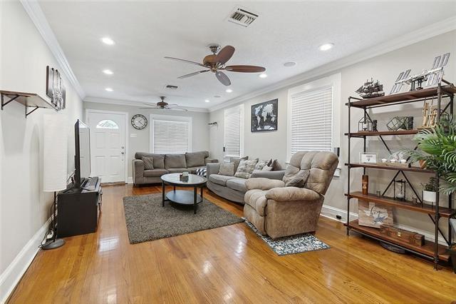 living room with hardwood / wood-style flooring, ceiling fan, and crown molding