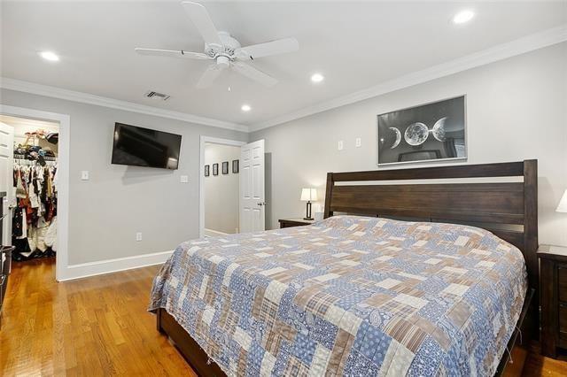 bedroom with hardwood / wood-style floors, a walk in closet, ceiling fan, crown molding, and a closet