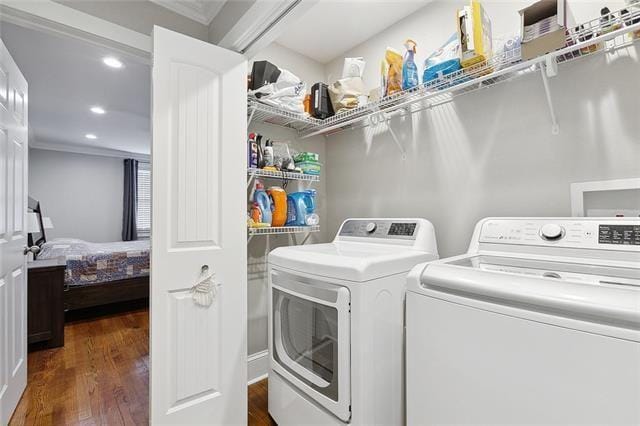 washroom featuring dark hardwood / wood-style flooring, ornamental molding, and washing machine and clothes dryer