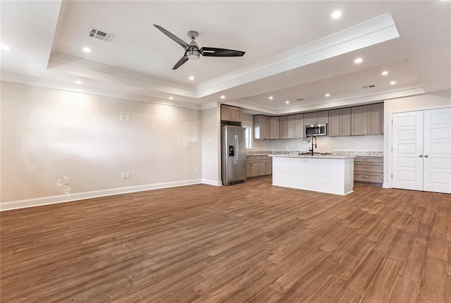 kitchen with sink, a center island with sink, dark hardwood / wood-style floors, a raised ceiling, and stainless steel appliances