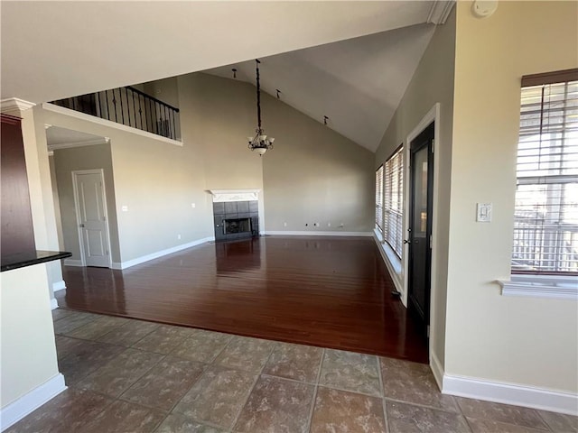 unfurnished living room with an inviting chandelier, dark wood-type flooring, a fireplace, and high vaulted ceiling