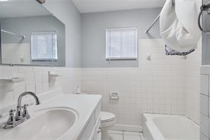 full bathroom with washtub / shower combination, tile patterned flooring, tile walls, vanity, and toilet