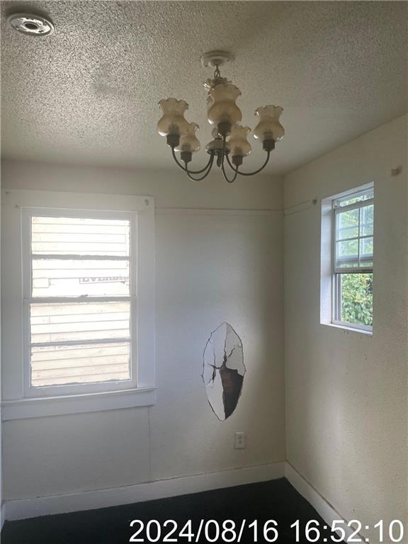 interior space with a textured ceiling, baseboards, and an inviting chandelier