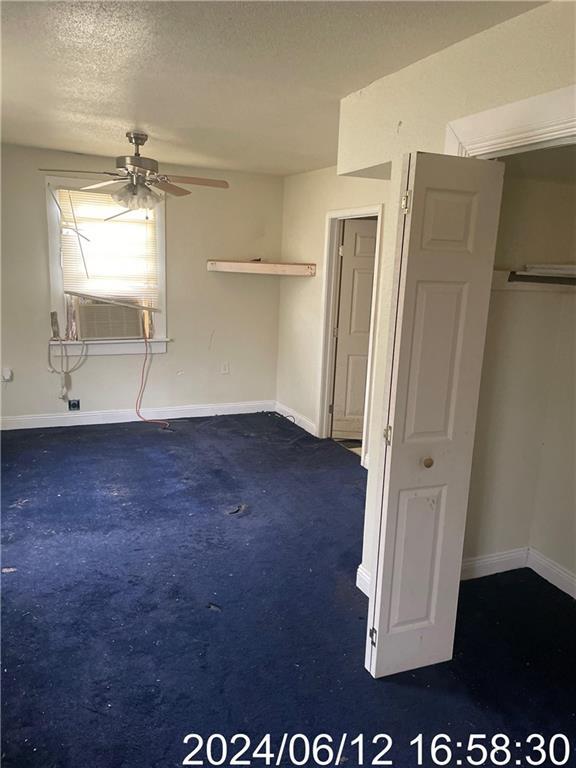 unfurnished bedroom featuring baseboards, cooling unit, dark colored carpet, and a textured ceiling