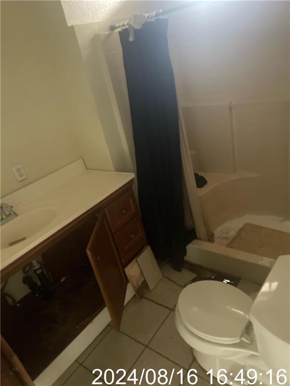 bathroom with curtained shower, vanity, toilet, and tile patterned floors