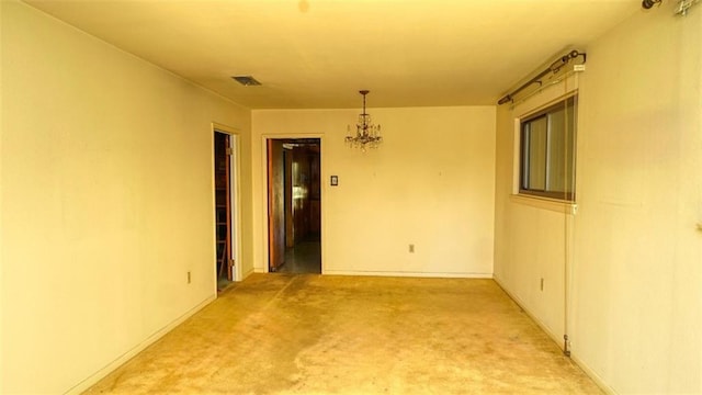 carpeted spare room featuring a notable chandelier