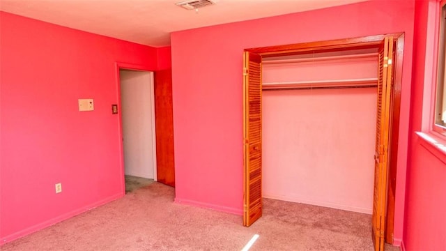 unfurnished bedroom featuring light carpet and a closet