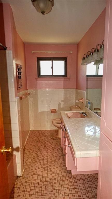 bathroom with vanity, toilet, and tile walls