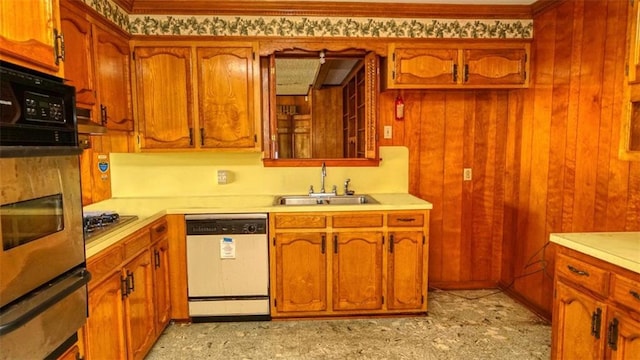 kitchen featuring sink, dishwasher, oven, stainless steel gas stovetop, and wood walls