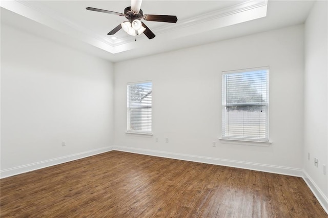 empty room with a tray ceiling, ornamental molding, ceiling fan, and hardwood / wood-style flooring