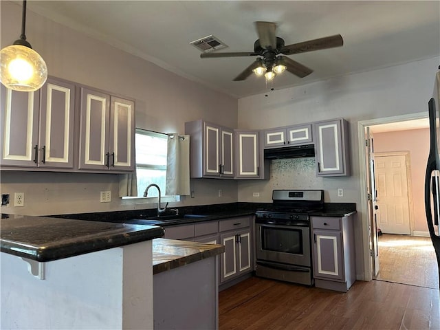 kitchen with stainless steel gas stove, sink, a breakfast bar area, hanging light fixtures, and kitchen peninsula