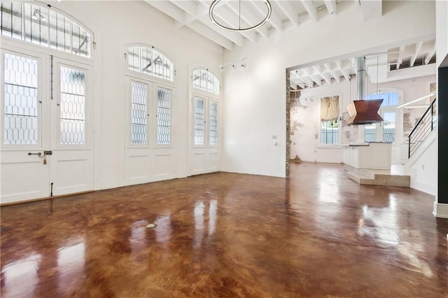 entryway featuring beamed ceiling, concrete floors, and a high ceiling