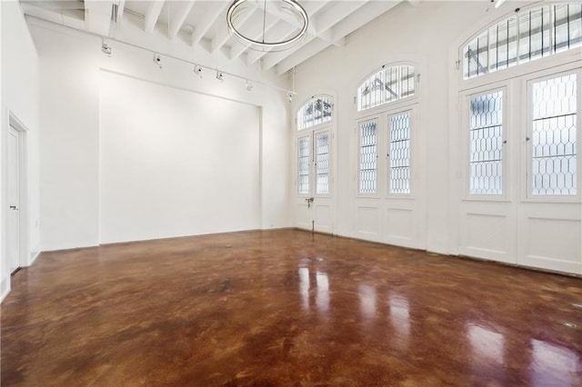 interior space with beam ceiling, french doors, and a high ceiling