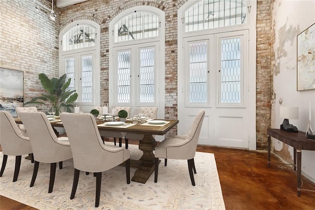 dining area featuring a towering ceiling, french doors, and brick wall