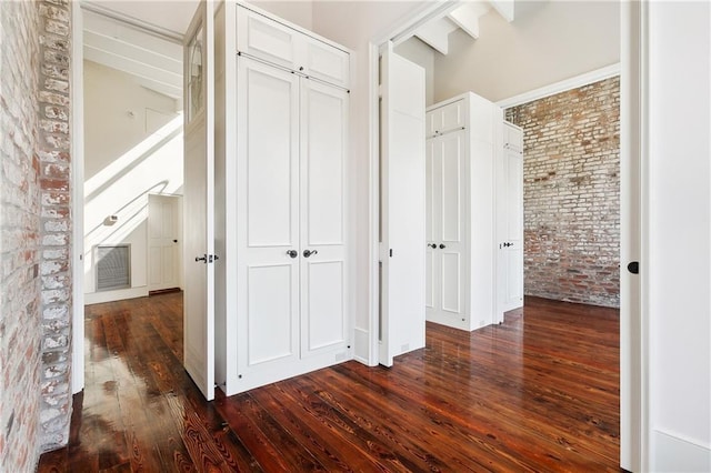 corridor featuring brick wall and dark hardwood / wood-style floors