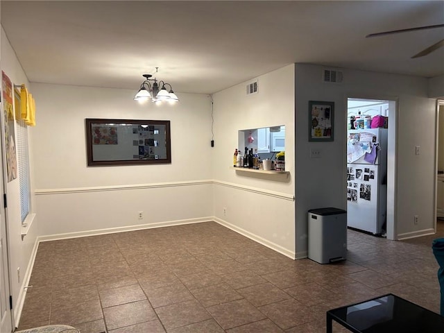 unfurnished dining area featuring ceiling fan with notable chandelier