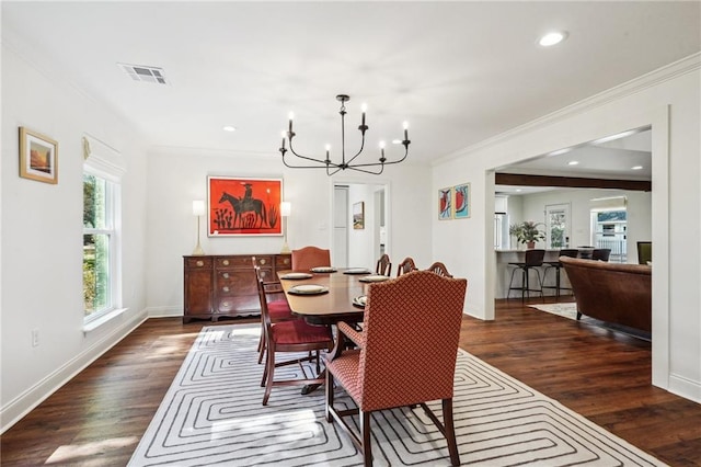 dining space featuring dark hardwood / wood-style flooring, crown molding, and a chandelier