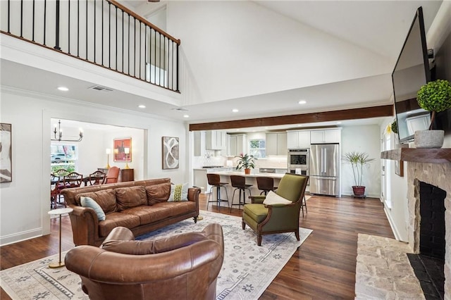 living room with a stone fireplace, a chandelier, ornamental molding, a towering ceiling, and hardwood / wood-style floors