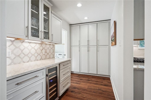 kitchen featuring dark hardwood / wood-style floors, white cabinetry, backsplash, beverage cooler, and light stone counters