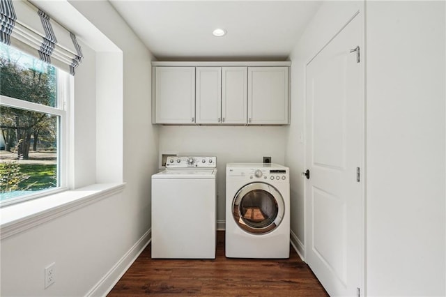 clothes washing area featuring cabinets, dark hardwood / wood-style floors, and washer and clothes dryer