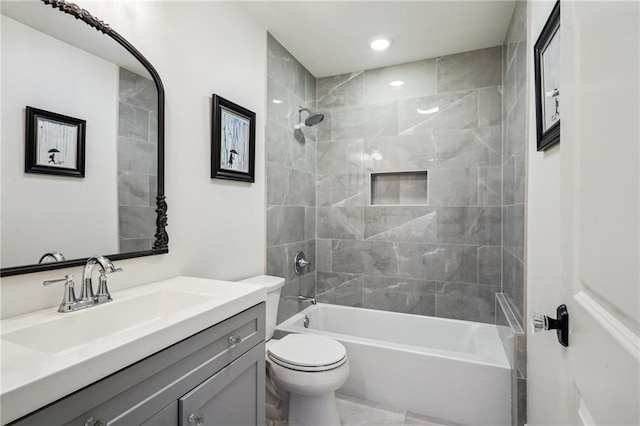 full bathroom featuring vanity, tiled shower / bath combo, and toilet