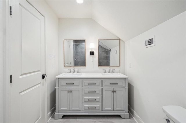 bathroom with lofted ceiling, toilet, and vanity