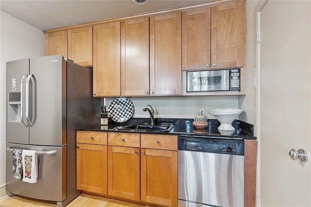 kitchen featuring stainless steel appliances, sink, and dark stone countertops