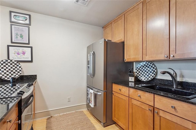 kitchen with electric stove, sink, dark stone countertops, stainless steel refrigerator with ice dispenser, and light hardwood / wood-style flooring