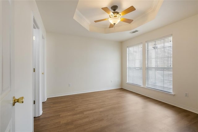 empty room with crown molding, dark hardwood / wood-style floors, ceiling fan, and a tray ceiling