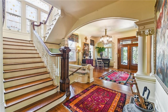 foyer with hardwood / wood-style floors, french doors, a chandelier, and ornate columns