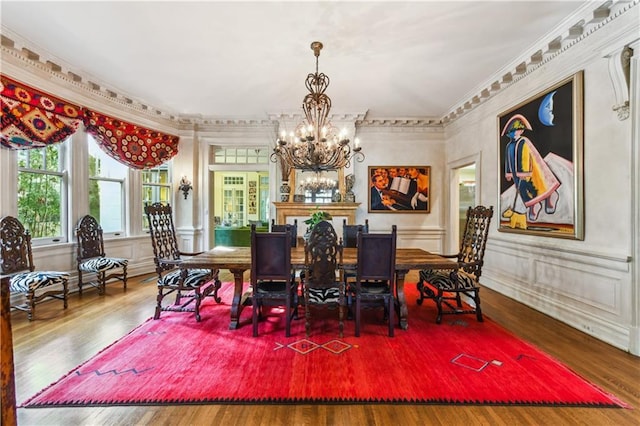 dining space with an inviting chandelier, wood-type flooring, and ornamental molding