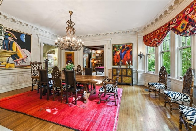 dining area with hardwood / wood-style flooring, crown molding, and a notable chandelier